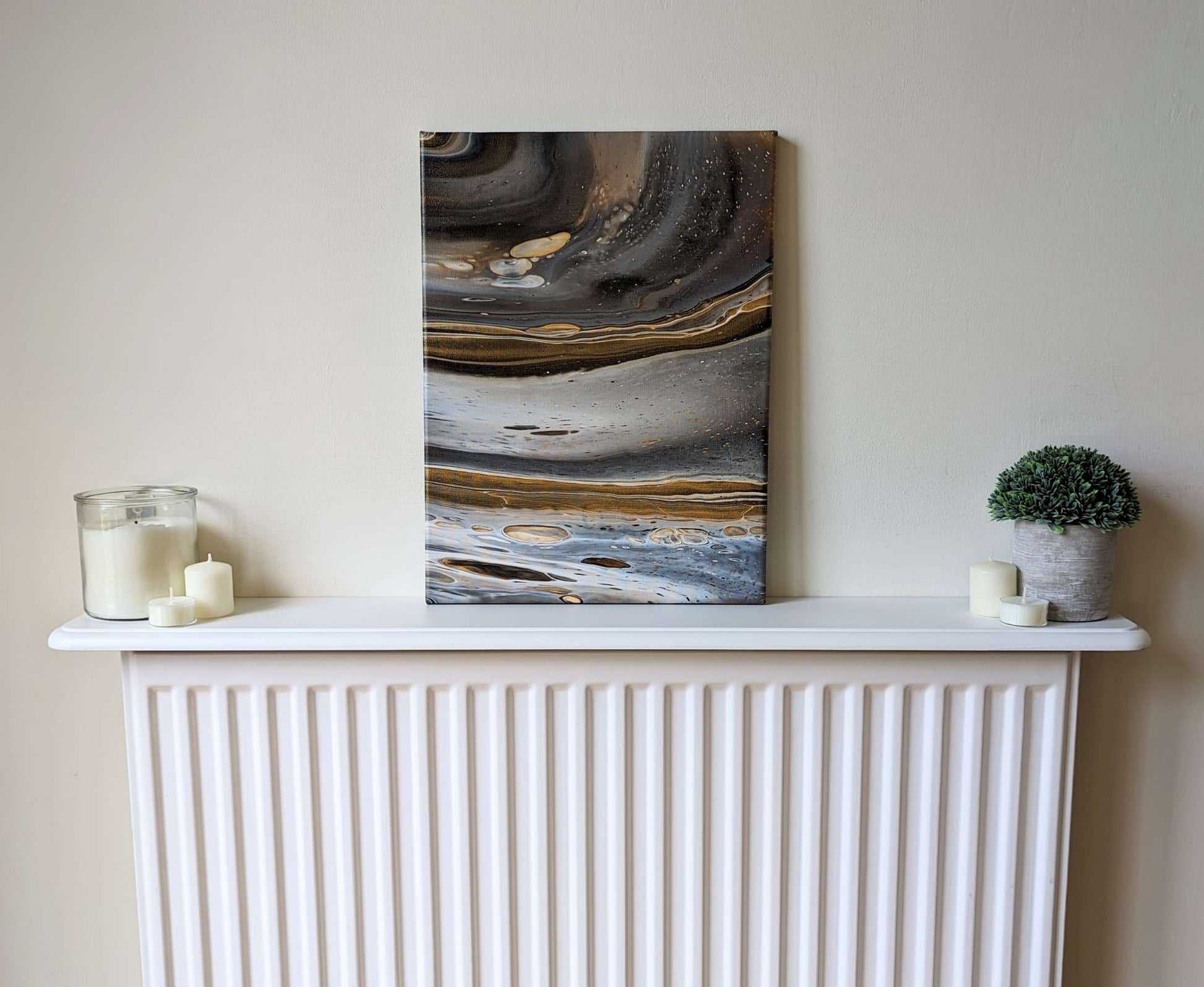 Canvas on shelf – frontal view of original abstract painting in grey hues with gold made with professional grade acrylic paint.