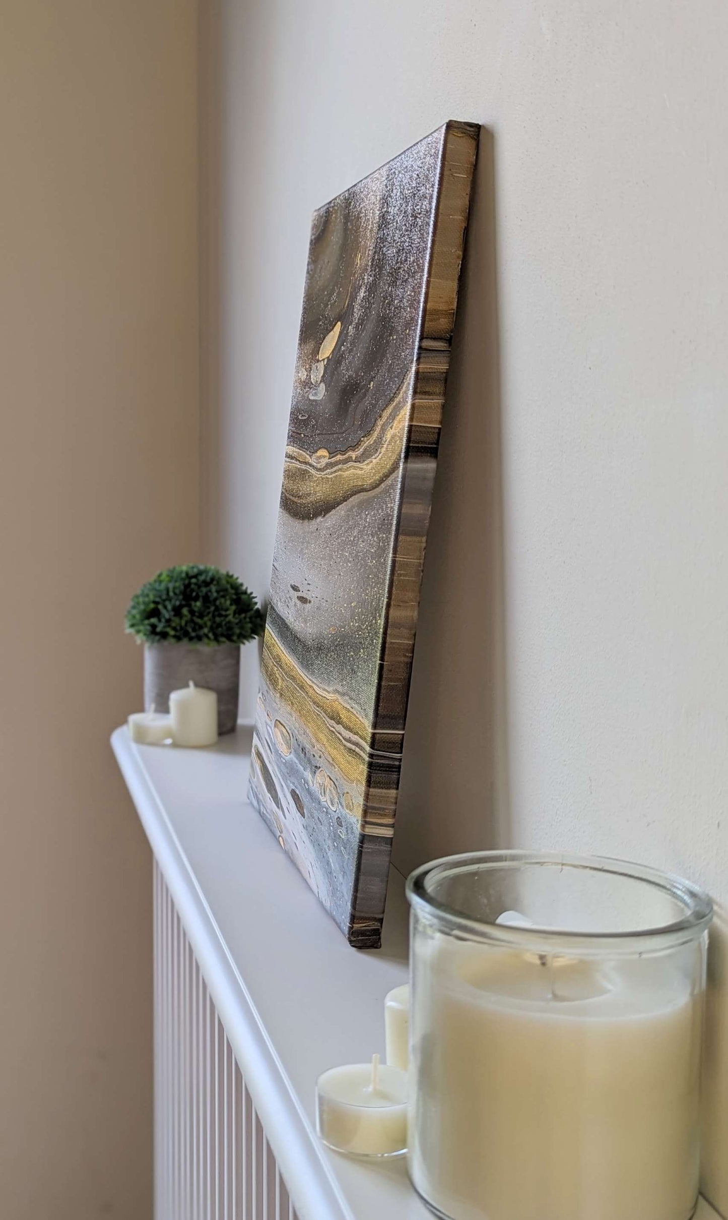 Canvas on shelf – side view of original abstract painting in grey hues with gold made with professional grade acrylic paint.