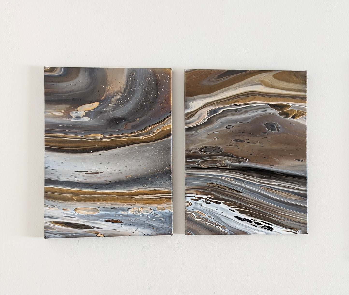 Two canvases on wall – frontal view of original abstract diptych in grey hues with gold made with professional grade acrylic paint.