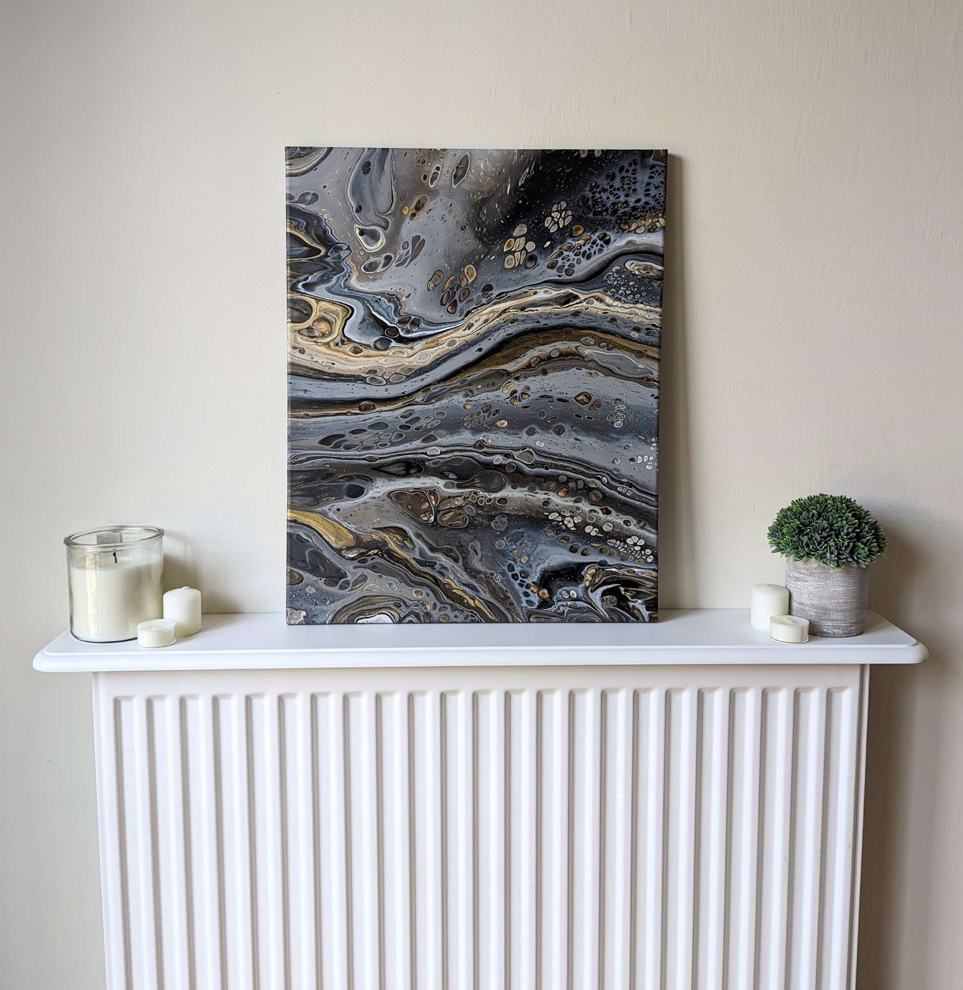 Canvas on shelf – frontal view of original abstract painting made in grey hues with gold made with professional grade acrylic paint.