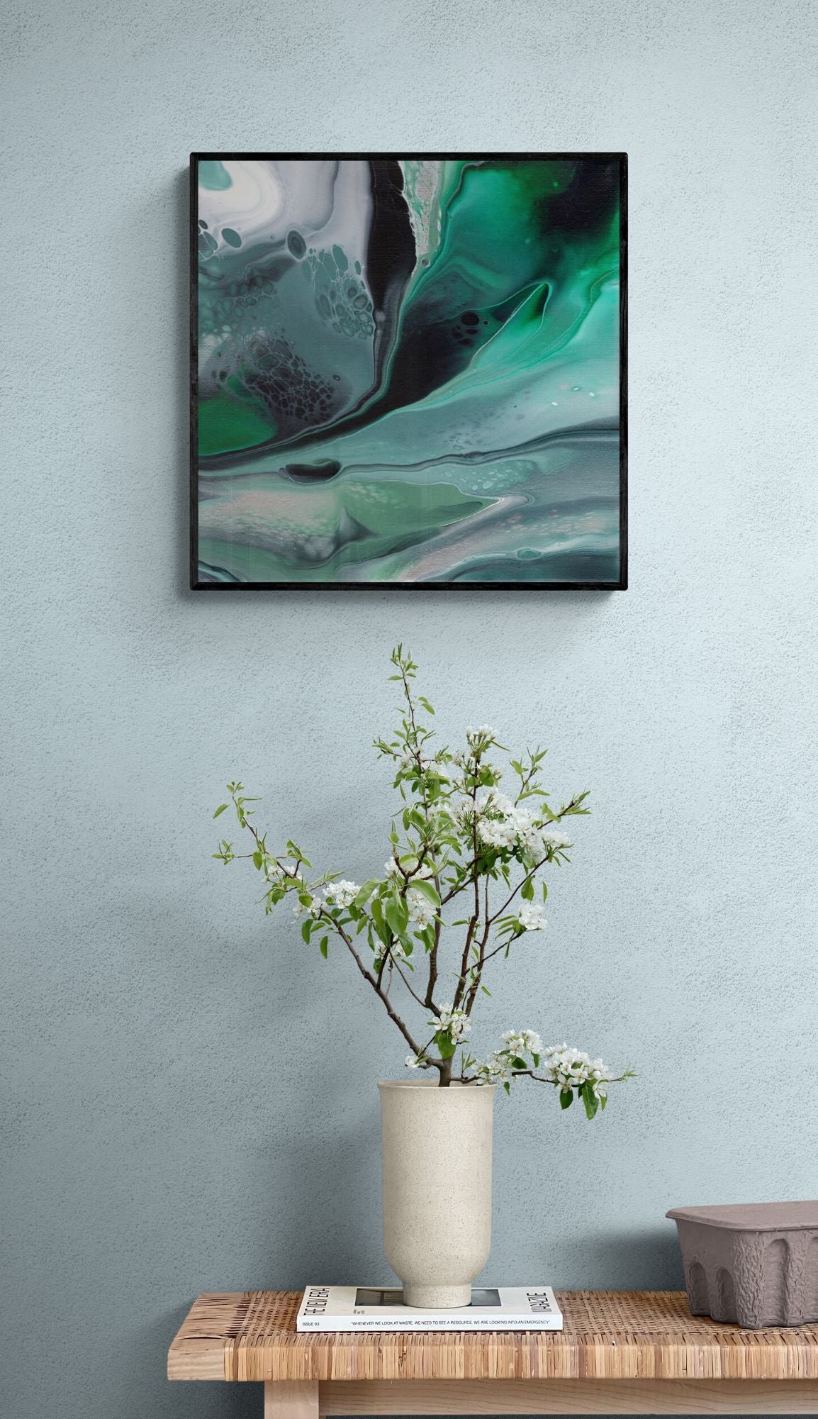 a 50x50 cm framed print over a side table with a plant on it.