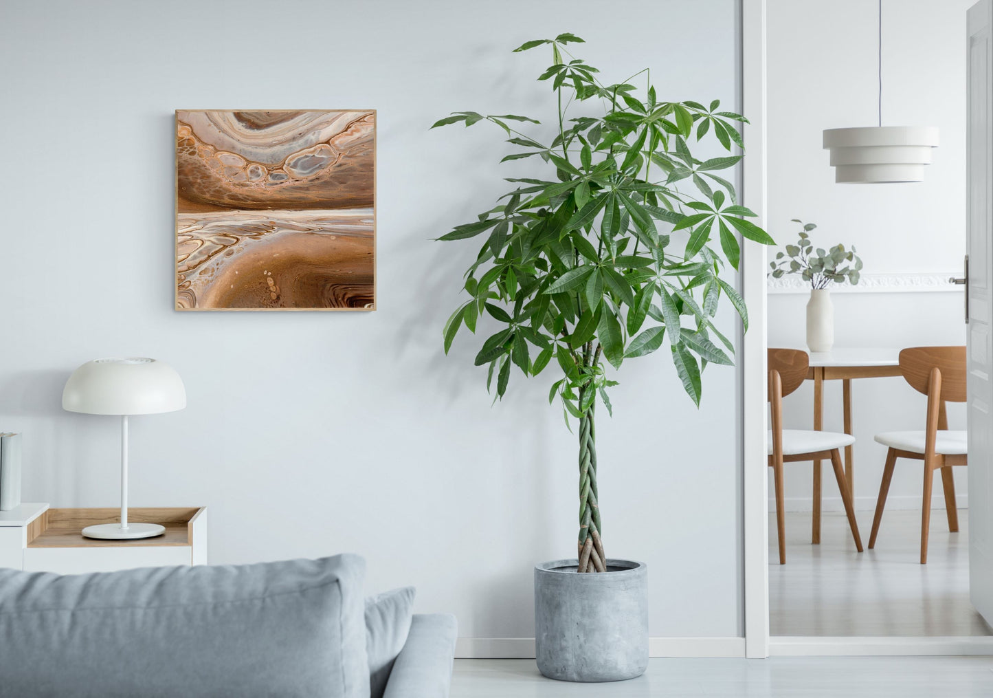 a 70x70 cm framed print in soothing neutral tones in a bright living room with a large plant