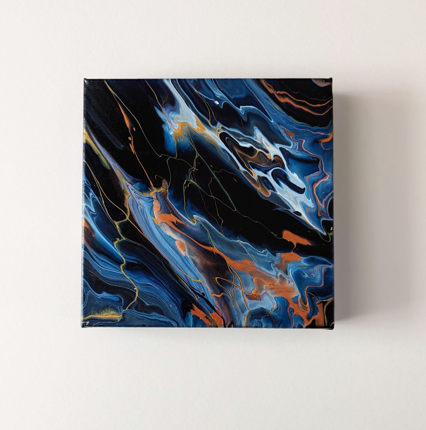 Canvas on wall – frontal view of original abstract painting made with Prussian blue and gold professional grade acrylic paint.