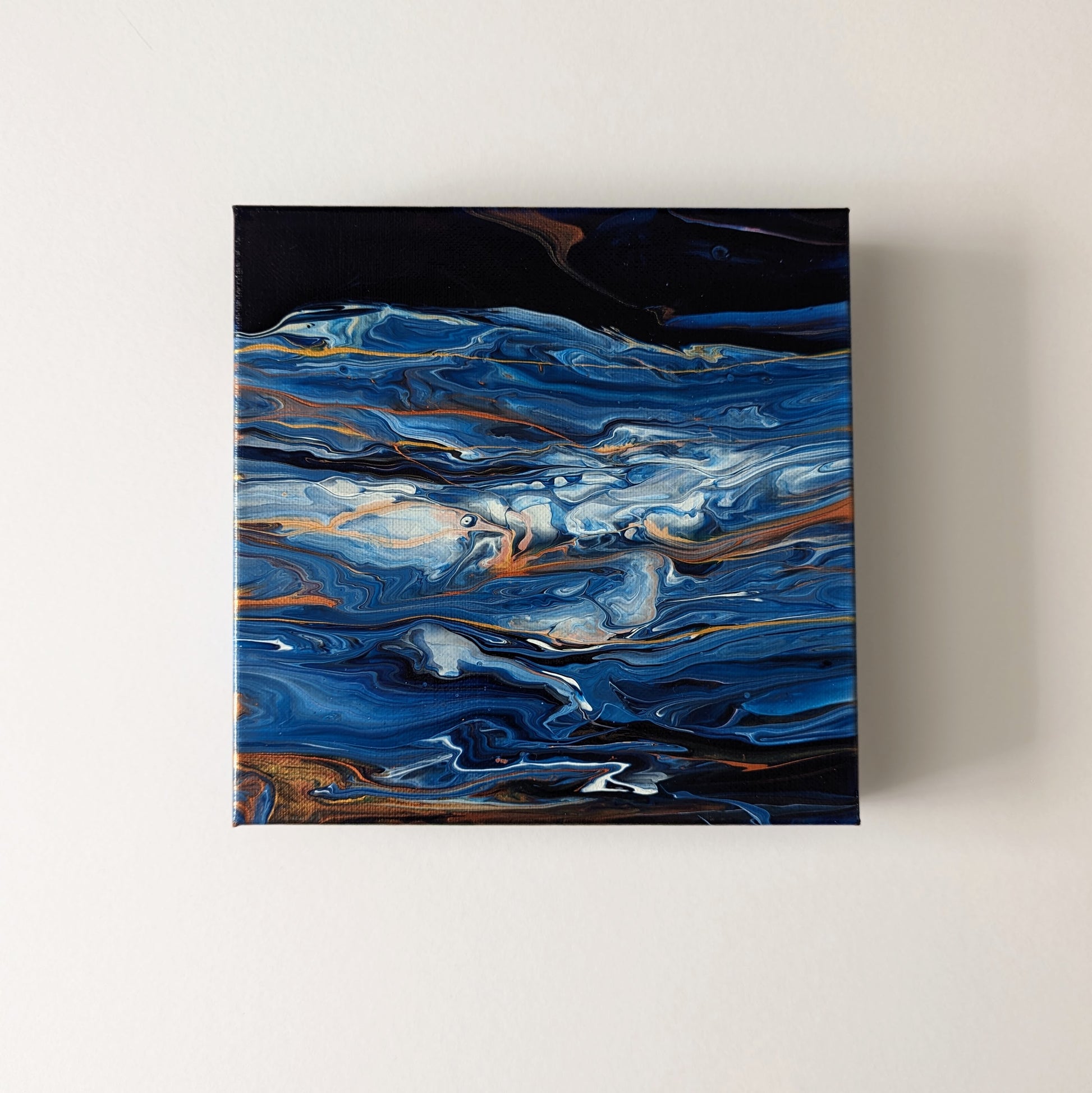 Canvas on wall – frontal view of original abstract painting made with Prussian blue and gold professional grade acrylic paint.
