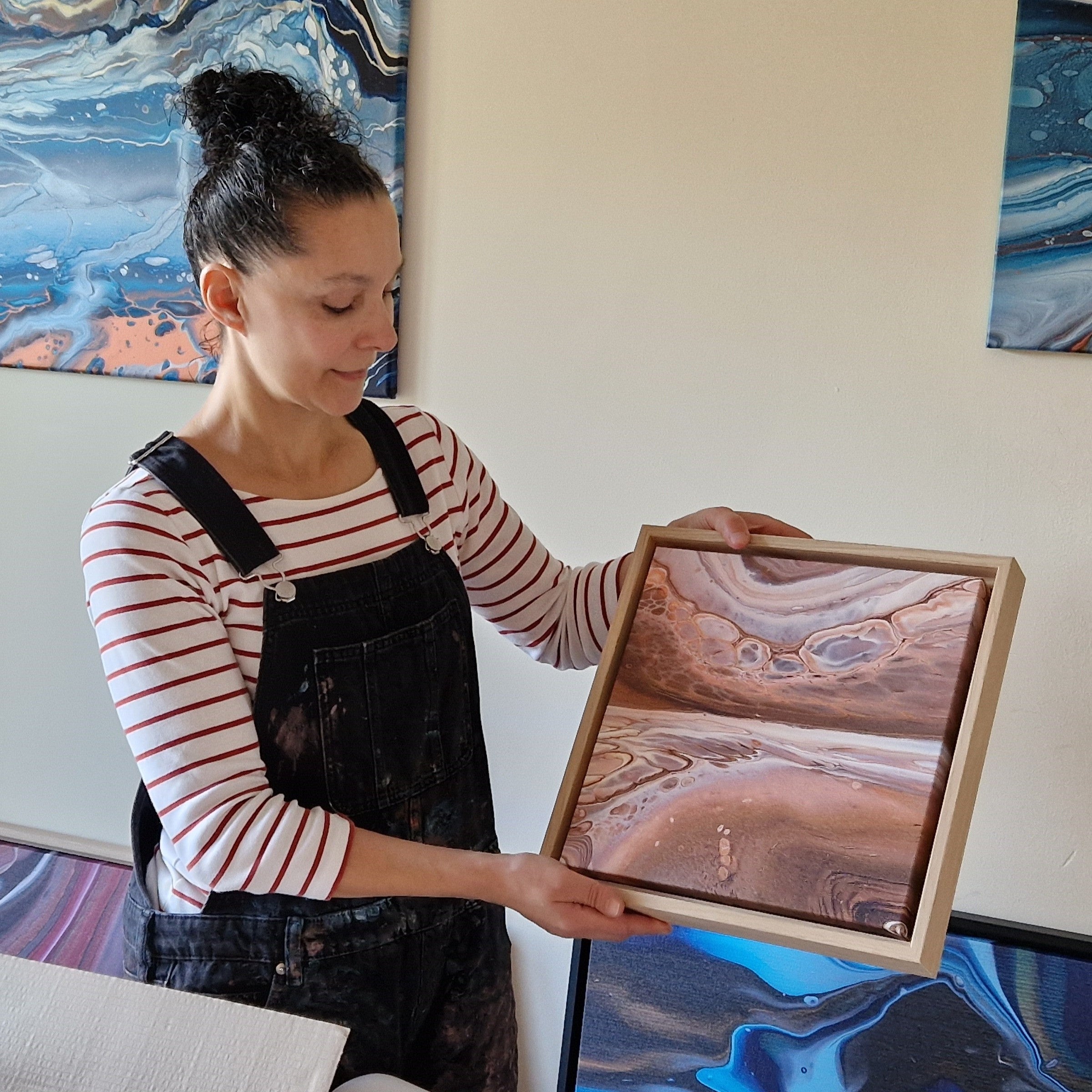 Artist holding a small canvas print in oak frame.
